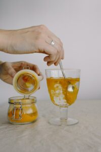 Crop hands adding turmeric in glass of hot water in morning