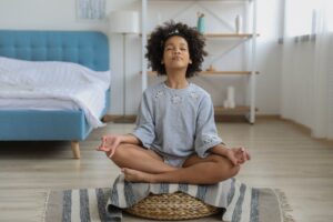 Black girl meditating in room with eyes closed